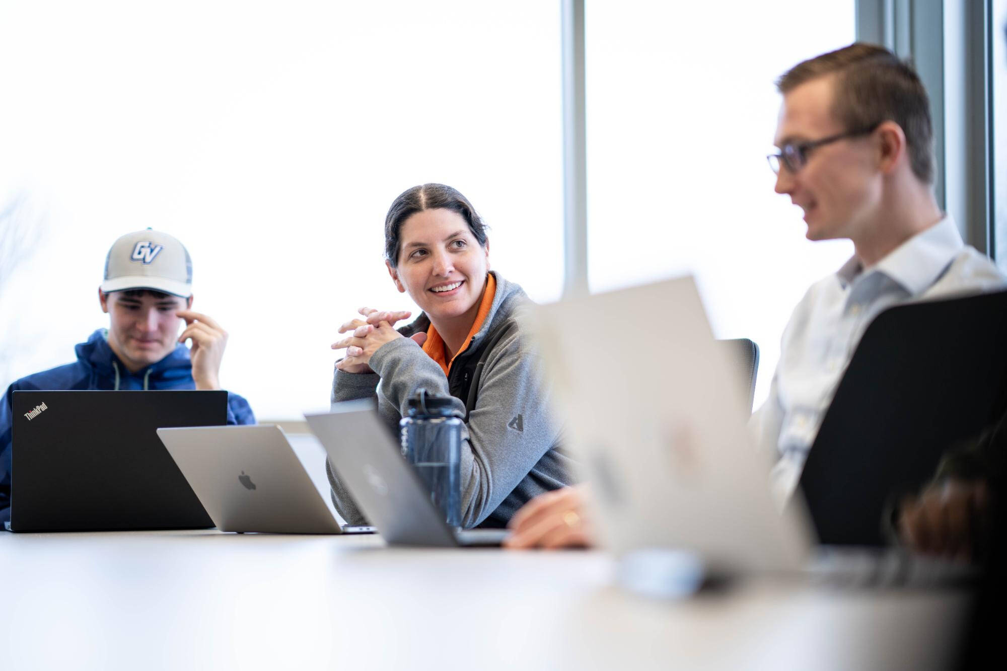 Individuals with laptops conversing at a table